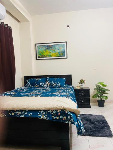 a bedroom with a bed with a blue comforter at Uttara Furnished Apartment in Ābdullāpur