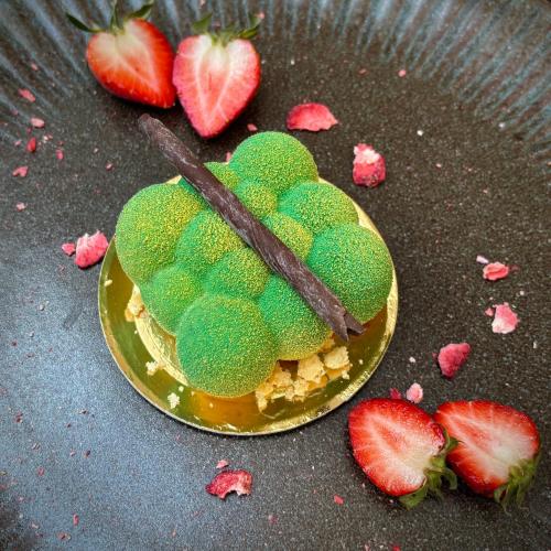 a green dessert on a plate next to strawberries at Hotel Ferreus Modern Art Deco in Kraków