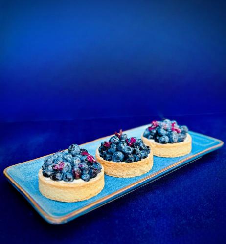three blueberry pies on a blue plate on a table at Hotel Ferreus Modern Art Deco in Kraków