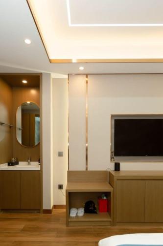 a living room with a television and a sink at 万信至格酒店乌鲁木齐机场德港万达店 in Ürümqi