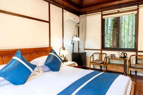 a bedroom with a bed with blue and white pillows at Liuchunwu Resort in Tianmu Mountain in Menkou