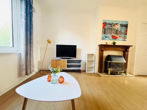 a living room with a white table and a tv at Lovely Maindoor flat at Murrayfield with Gardens in Edinburgh