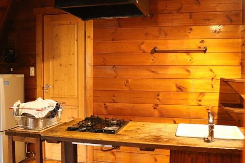 a kitchen with a stove and a wooden wall at Kitakaruizawa Sweet Grass - Vacation STAY 22104v in Kita-karuizawa