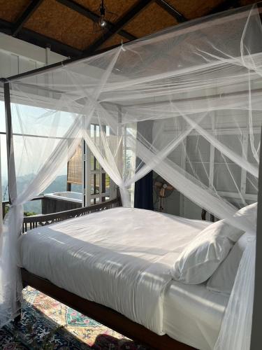a bedroom with a white canopy bed with curtains at 4000Dao- A Hilltop Hideaway & Experience in Doi Tung 