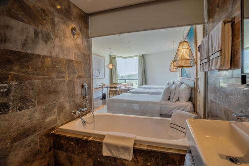 a bathroom with a tub and a bedroom with a bed at Melia Danang Beach Resort in Da Nang