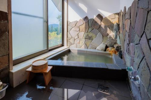 einen Whirlpool in einem Zimmer mit einer Steinmauer in der Unterkunft Miyama - Zao Sansuien Gaia Resort - Vacation STAY 54108v in To-katta