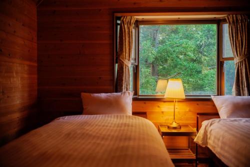 two beds in a room with a window at Gubo Satoyama SUITE Miyagi Zao - Vacation STAY 54123v in To-katta