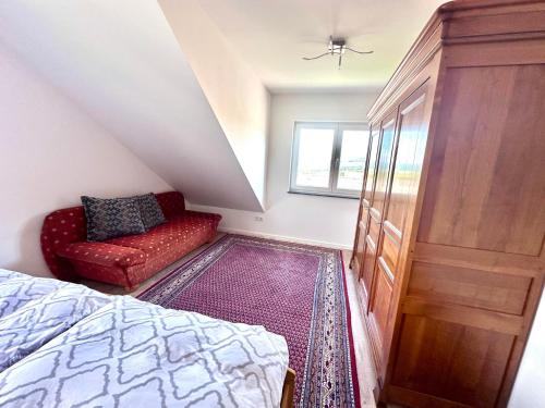 a bedroom with a bed and a red chair at Ferienwohnung Rundblick Rhön in Ehrenberg