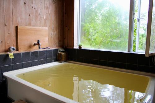 una vasca da bagno riempita d'acqua accanto a una finestra di - F,J Forest Zao - Zao Sansuien - Gaia Resort - Vacation STAY 54193v a To-katta