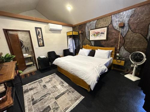 a bedroom with a bed and a desk with a fan at Gumaan Resort in Skardu