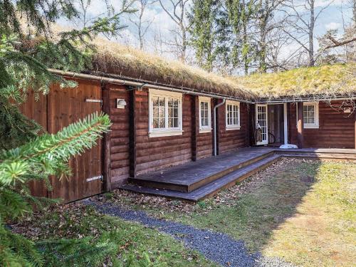 uma cabana de madeira com telhado de grama e uma varanda em 8 person holiday home in Frederiksværk-By Traum em Frederiksværk