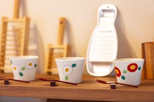 three white cups sitting on a wooden shelf at Hot Spring Villa - Inroan - Vacation STAY 54229v in To-katta