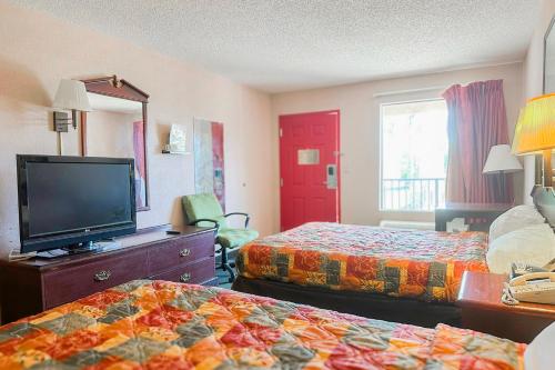a hotel room with two beds and a flat screen tv at OYO Hotel East Macon I-75 in Macon