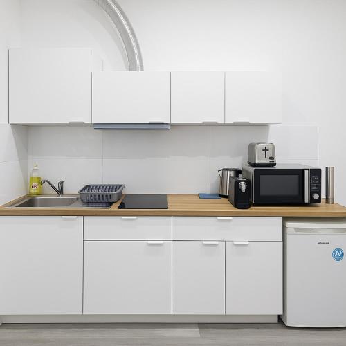a kitchen with white cabinets and a microwave at cosy studio hydraulique in Brussels