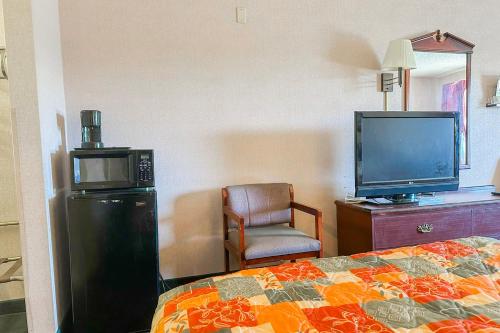 a hotel room with a bed and a tv and a chair at OYO Hotel East Macon I-75 in Macon
