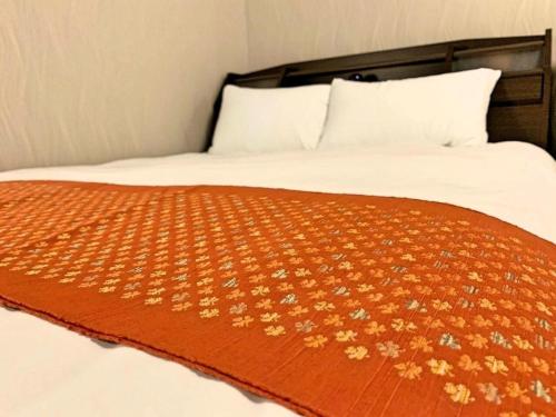 a bed with a orange blanket with flowers on it at Sunrise Sendai Honcho Building 3F - Vacation STAY 54319v in Sendai