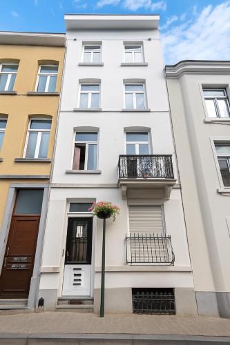 a white building with a balcony on a street at cosy studio hydraulique in Brussels