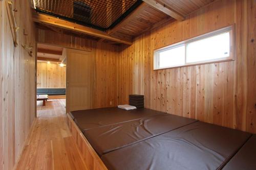 a large bed in a wooden room with a window at Kitakaruizawa Sweet Grass - Vacation STAY 61669v in Kita-karuizawa