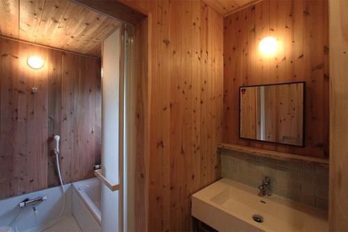 a bathroom with wooden walls and a sink and a mirror at Kitakaruizawa Sweet Grass - Vacation STAY 61669v in Kita-karuizawa