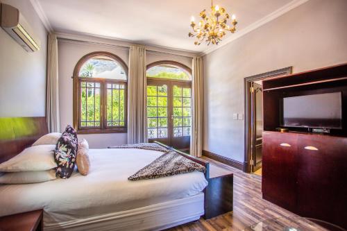 a bedroom with a large bed and a flat screen tv at Cape Riviera Guesthouse in Cape Town