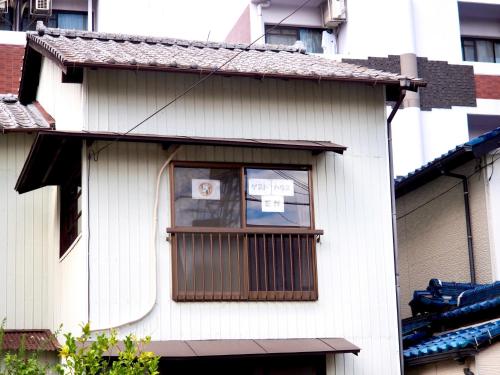 a white house with a window with a sign in it at Guesthouse EN - Vacation STAY 85401v in Kitakyushu