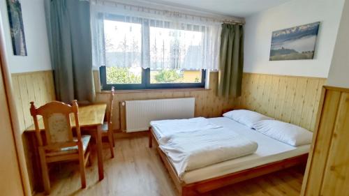 a bedroom with a bed and a table and window at Pokoje Gościnne Barka - 300m do RESTAURACJI - 900m do JEZIORA i VELO CZORSZTYN in Kluszkowce