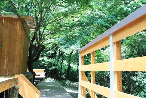 a wooden deck with a bench in the woods at Guesthouse Nagomi in Minamiaso - Vacation STAY 17895 in Minami Aso