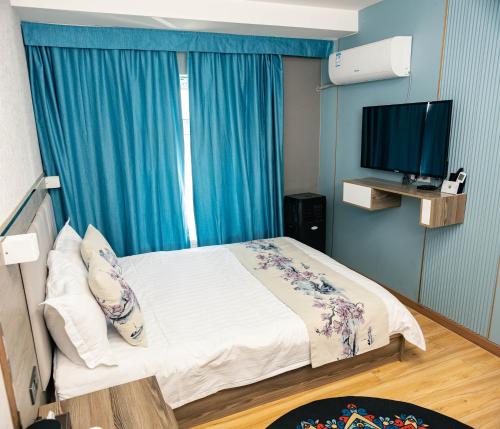 a bedroom with a bed with blue curtains and a television at Khovuun hotel in Dalandzadgad