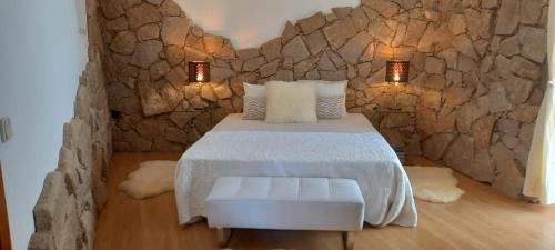 a bedroom with a bed and a stone wall at Casa de Freixo in Freixo de Espada à Cinta