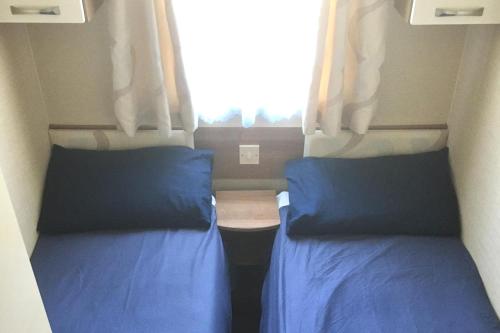 two beds in a small room with a window at Beautiful 3 bed caravan SouthviewPark Skegness in Skegness