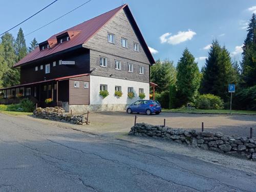 a blue car parked in front of a large barn at Horsky hotel Sport in Josefuv dul