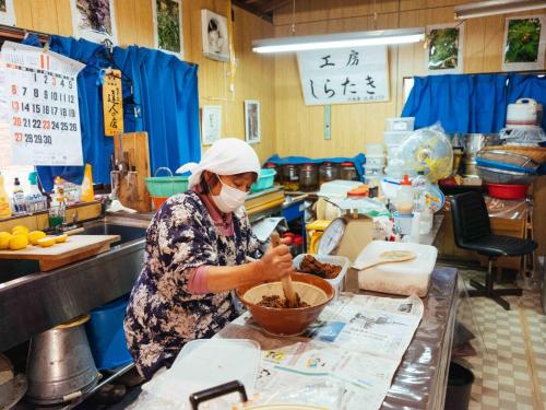 a woman in a kitchen preparing food in a bowl at Shirataki no yado - Vacation STAY 29763v in Higashimiyoshi