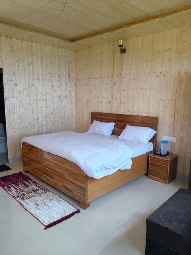 a bedroom with a large bed with white sheets at Kanatal Majestic Resort by RIHS in Kanatal