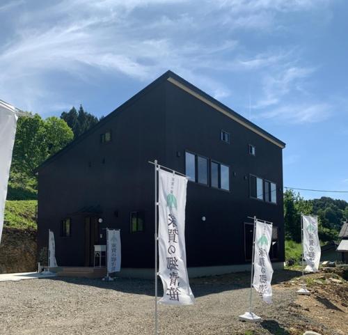 ein schwarzes Gebäude mit Flaggen davor in der Unterkunft Ieka Village Kiyosasawa - Vacation STAY 71845v in Sadamitsu