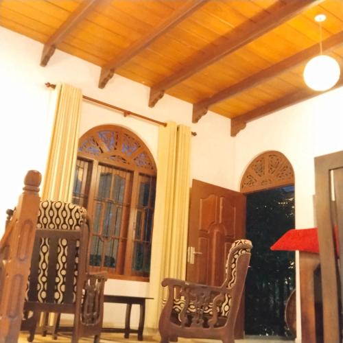 a living room with two chairs and a door at Tharul Home in Bentota