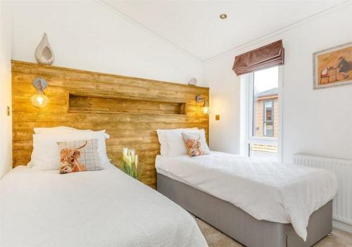 Sanctuary Caledonia Hot tub lodge في حصن أوغسطس: غرفة نوم بها سريرين وجدار خشبي