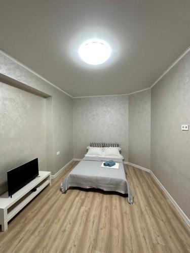 a bedroom with a bed and a flat screen tv at Квартира на Торайгырова in Almaty