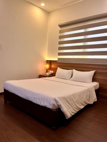 a bedroom with a large white bed with a window at Lantern Hotel in Ho Chi Minh City