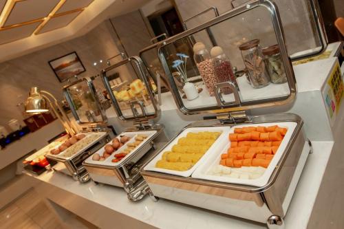 a buffet with several trays of different types of food at 万信至格酒店乌鲁木齐机场德港万达店 in Ürümqi