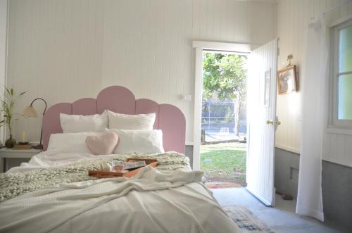 una camera da letto con un letto grande con testiera rosa di The Dairy at Cambewarra Estate Winery a Camberwarra