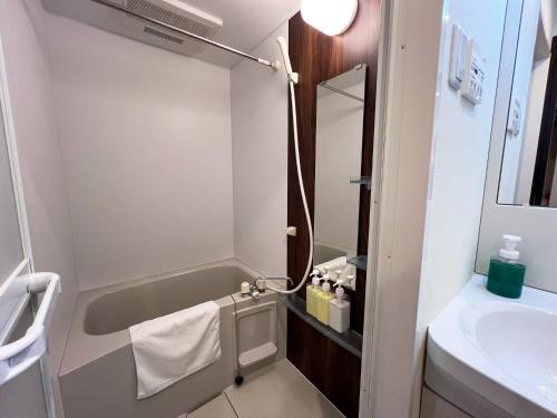 ein kleines Bad mit einer Badewanne und einem Waschbecken in der Unterkunft Lion Heiwa Odori - Vacation STAY 18062 in Hiroshima
