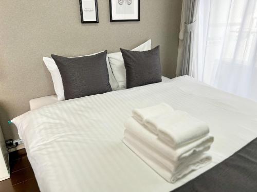 ein weißes Bett mit darauf gestapelten Handtüchern in der Unterkunft Lion Heiwa Odori - Vacation STAY 18061 in Hiroshima