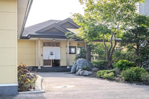 a yellow house with a rock in front of it at Private Inn Kazu - Vacation STAY 56401v in Abuta