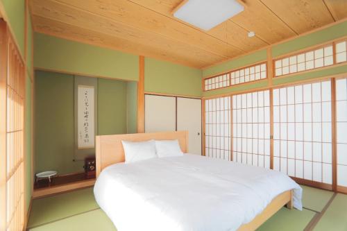 a bedroom with a white bed in a room with windows at Yufuin Waon no Yado - Vacation STAY 18114 in Yufuin