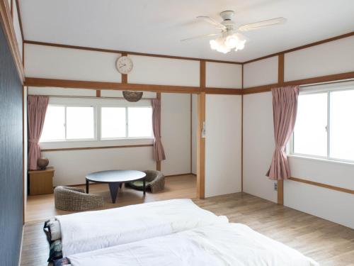 a bedroom with a bed and a table and windows at Yadokari 852 - Vacation STAY 56348v in Manazuru