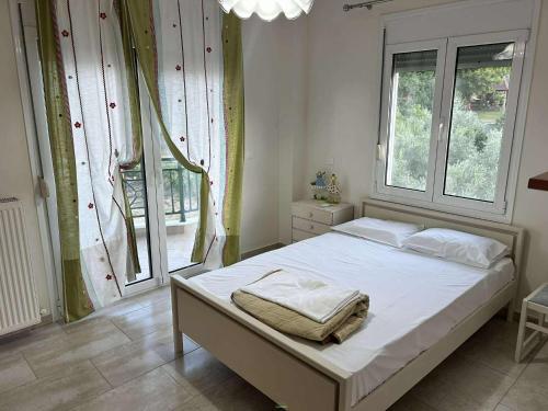 Un dormitorio con una cama con sábanas blancas y una ventana. en Sunnyhomes Livithra, en Leptokarya