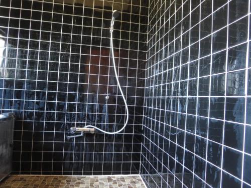 a black tiled bathroom with a shower with a hose at Hitachiota Studio - Vacation STAY 18131 in Hitachi Ota
