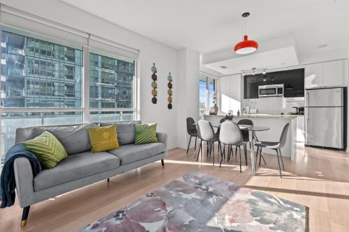 a living room with a gray couch and a kitchen at Modern New 2Bd 2Ba &Den Condo with Balcony in Toronto