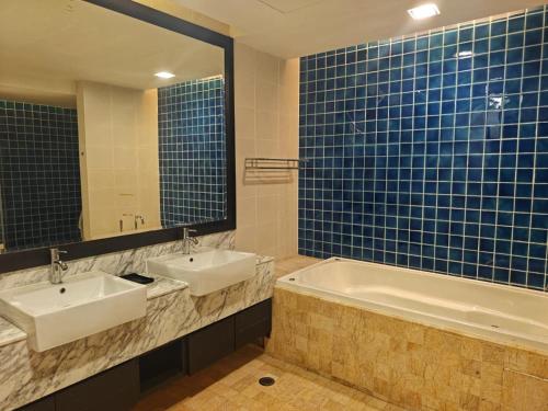 a bathroom with two sinks and a tub and a mirror at Sabah Beach Villas & Suites in Kota Kinabalu