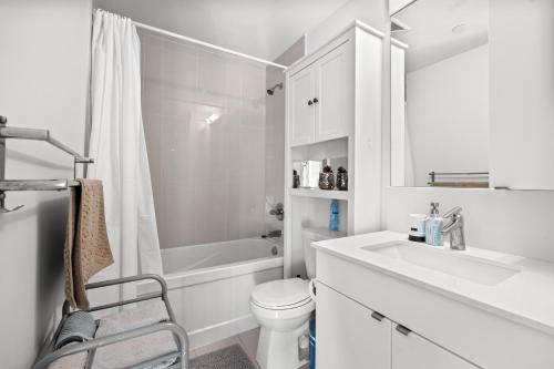 a white bathroom with a toilet and a sink at Modern New 2Bd 2Ba &Den Condo with Balcony in Toronto